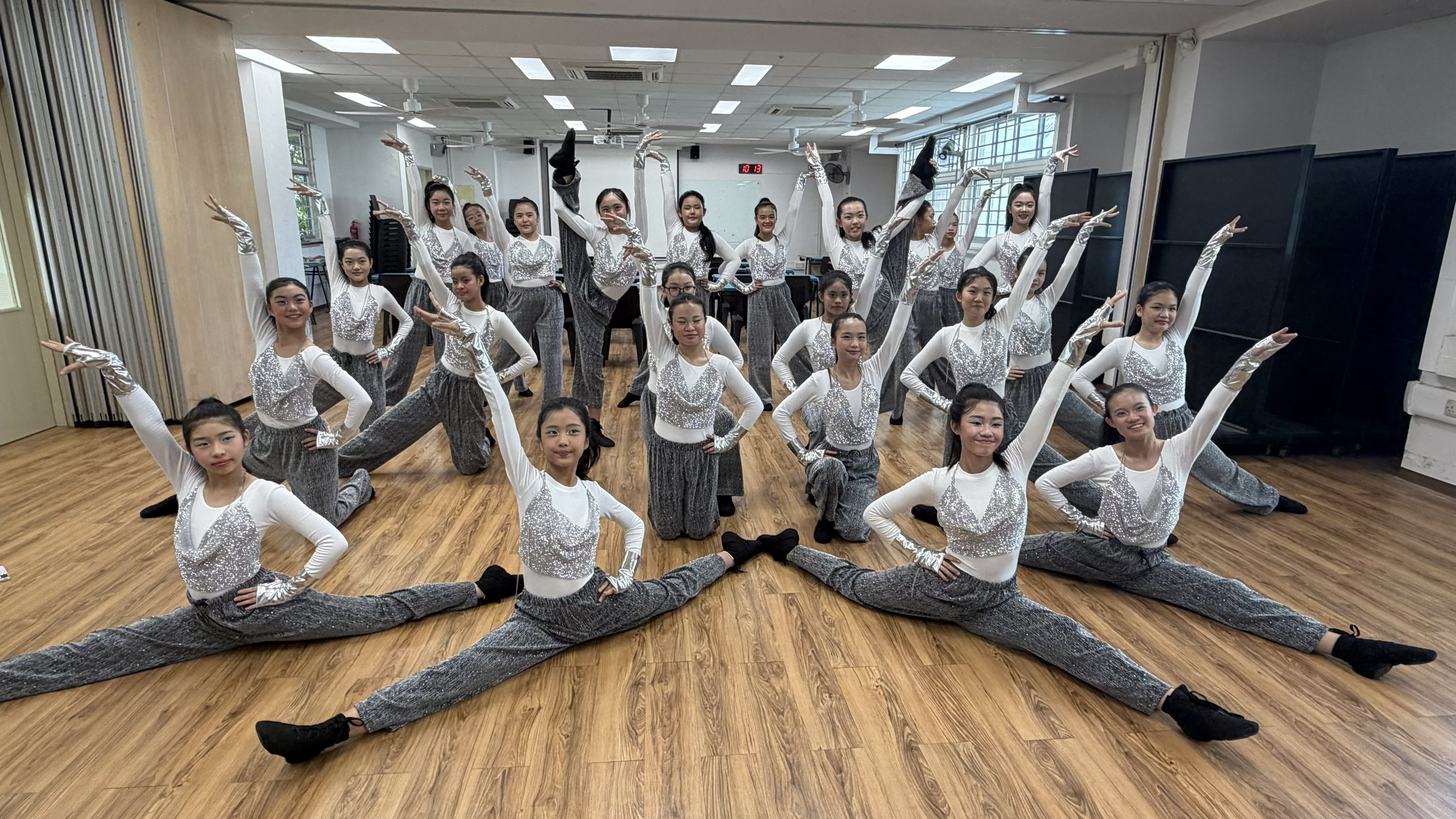 Photograph of a dance group posing with some executing full splits and others in coordinated poses.